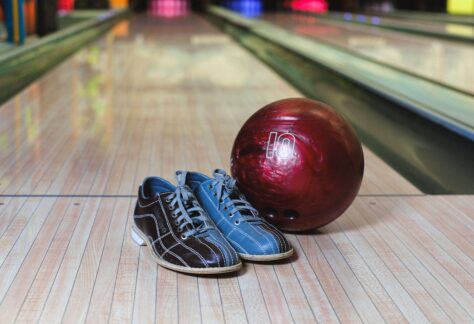 Bowling shoes and a red ball on a wooden lane, ready for action.